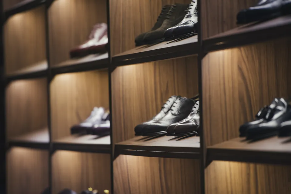 Beleuchtetes Holzregal mit eleganten Herrenschuhen